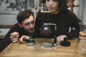 Vintage couple preparing coffee with vacuum coffee maker.Coffee shop photo