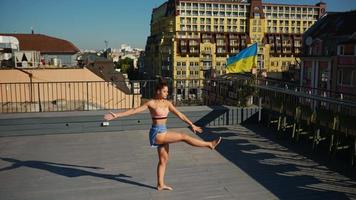 Young fit woman stretches and exercises outdoors on concrete surface on a sunny day in the city video