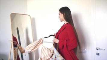 junge Frau probiert Kleidung vor einem Ganzkörperspiegel im Schlafzimmer an video