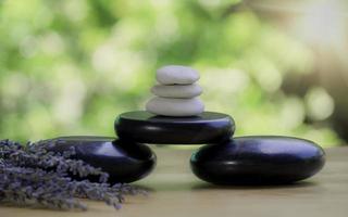 Balance and wellness or health concept with pile of black spa stones on wood and spikes of flowering lavender with aromatherapy. Side view and landscape composition feel relaxed. photo