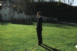 groom standing on the grass photo