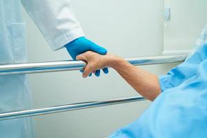 Asian elder senior woman patient holding bed rail while lie down with hope waiting her family in hospital. photo