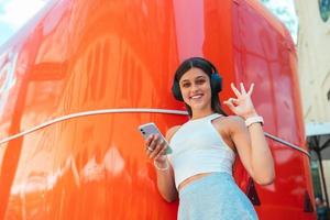 Young woman listening music with wireless headphones in the street photo