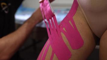 Physiotherapist applying kinesio tape on female patient. photo