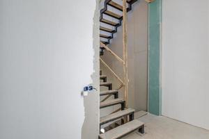 empty white room without repair and furniture with scaffolding with wooden stairs photo