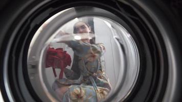 vista desde el interior de la secadora mientras la mujer tira la ropa y la ropa se cae