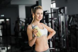 Beautiful athletic girl  poses in the gym with a yellow shaker. photo