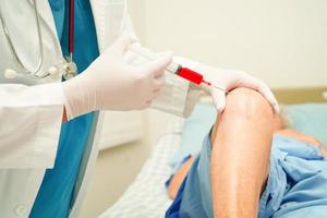 Asian doctor inject Hyaluronic acid platelet rich plasma into the knee of senior woman to walk without pain. photo