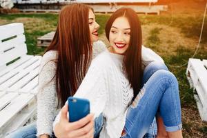 dos chicas haciendo selfie en el banco foto