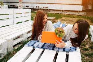 Girls lie on the bench and give each other gifts photo