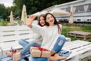 Two beautiful girls sitting on a bench photo