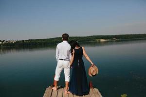 Young couple standing on a deck by the water photo
