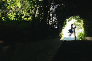 couple jumping in the end of tunnel with trees photo