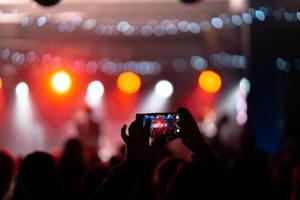 persona cerca de grabar video con teléfono inteligente durante un concierto. foto