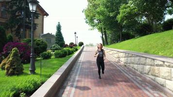 Adult woman with red hair runs outdoors on a brick paved pathway video