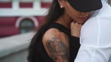 joven pareja de moda con tatuajes abrazados en una calle de la ciudad