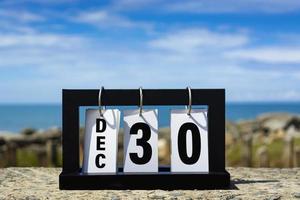 Dec 30 calendar date text on wooden frame with blurred background of ocean. photo