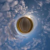 tiny planet in blue sky with beautiful clouds. Transformation of spherical panorama 360 degrees. Spherical abstract aerial view. Curvature of space. photo