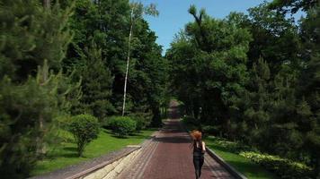 Adult woman with red hair runs outdoors on a brick paved pathway video