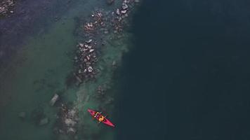 People in orange kayak paddle in flooded rock quarry video