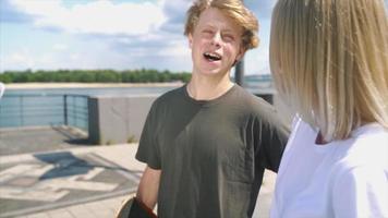 tiener- jongen en meisje wandelen en praten Aan een bocht zonnig dag in buitenshuis stad ruimte video