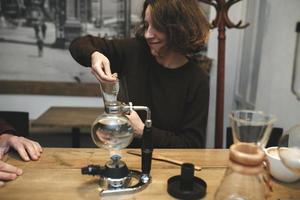 pareja vintage preparando café con cafetera al vacío. cafetería foto