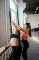 Active sportive woman stretching, young woman helping her photo