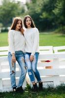 Two girls lean bench photo