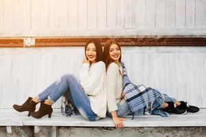 dos chicas se sientan en un banco en el parque foto