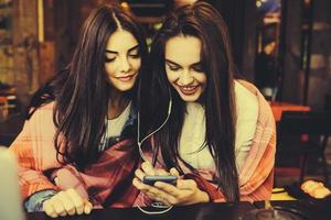 Two girl sitting listening to music with a smartphone photo