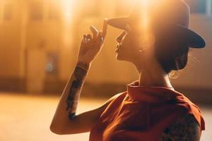 The young, attractive girl in a hat poses to the camera at night photo