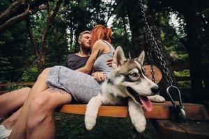 beautiful couple together with dog on a swing photo