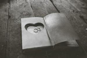 encantador libro vintage con corazón hecho a mano en el que descansa el anillo. foto