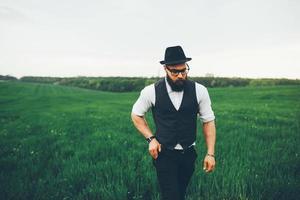 hombre con barba y gafas de sol caminando en el campo foto