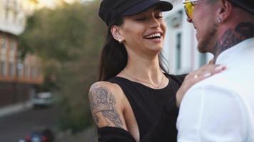 Young hip couple with tattoos embrace on a city street video