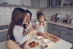 Mom and two daughters eat pancakes photo