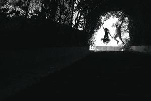 couple jumping in the end of tunnel with trees photo