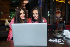 two girls watching something in laptop photo