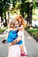 Woman hugs her daughter, holding her in her arms photo