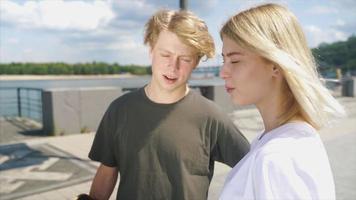 Teenage boy and girl walk and talk on a bight sunny day in outdoor city space video