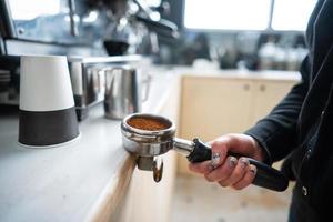 barista sosteniendo portafiltro con café molido foto