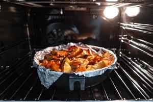 Baked potatoes with carrot and other spices in roasting pan. photo