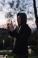 Young guy in the park takes a photo on two smartphones