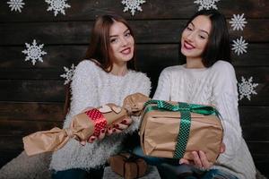 Two beautiful girls offer gifts to camera photo