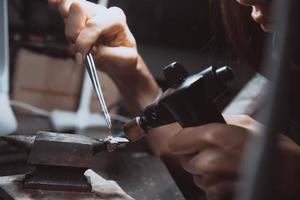 In the workshop, a woman jeweler is busy soldering jewelry photo