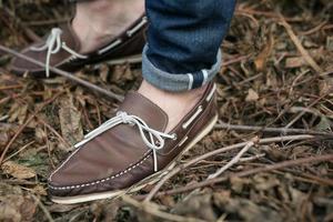 pies del hombre con botas auténticas y vaqueros de orillo, en el fondo de las ramas foto