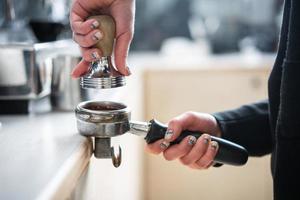 Barista presses ground coffee using tamper. photo