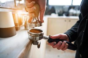 Barista presses ground coffee using tamper. photo