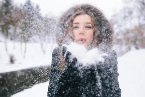 beautiful young woman blows snow photo