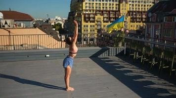 Young fit woman stretches and exercises outdoors on concrete surface on a sunny day in the city video